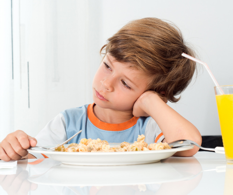 Smutné dítě sedící u stolu odmítá jídlo na talíři, problém s nechutenstvím.
